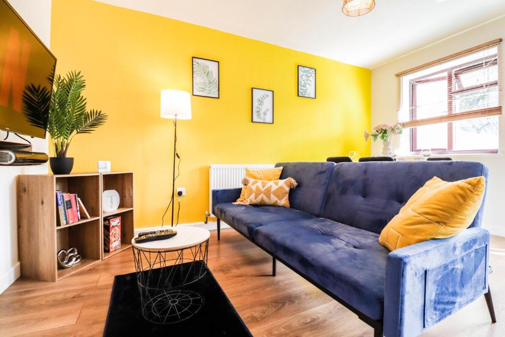 a living room with a blue couch and yellow walls at Spacious 1 bed flat-FREE Parking in New Bedfont