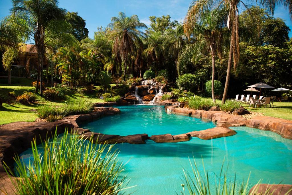 een zwembad in een tuin met een waterval op de achtergrond bij Ville Real Hotel in Santo Antônio do Leite