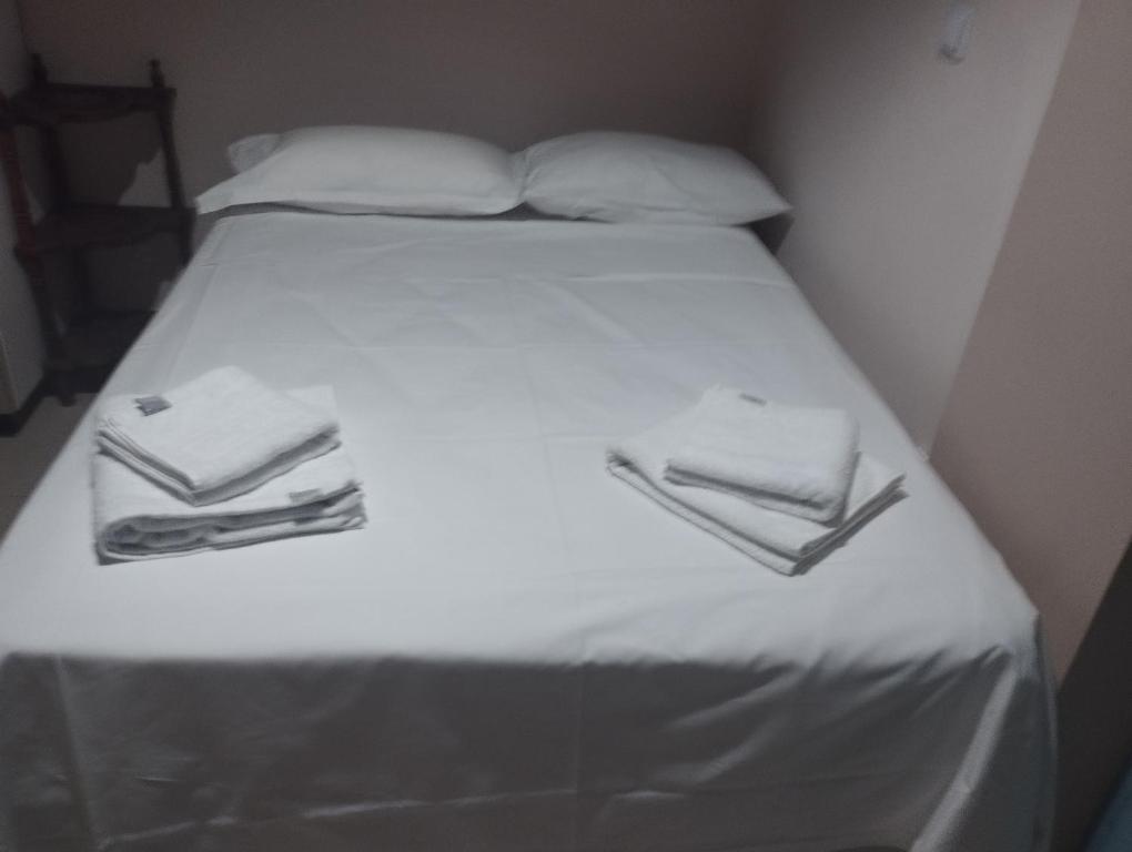 łóżko z białą pościelą i ręcznikami w obiekcie Στούντιο Στη Στοά Βαρβουτσή Νούμερο#7 w Kalamácie