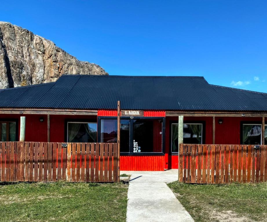 een rood gebouw met een zwart dak en een hek bij Hostel El Paredon in El Chalten