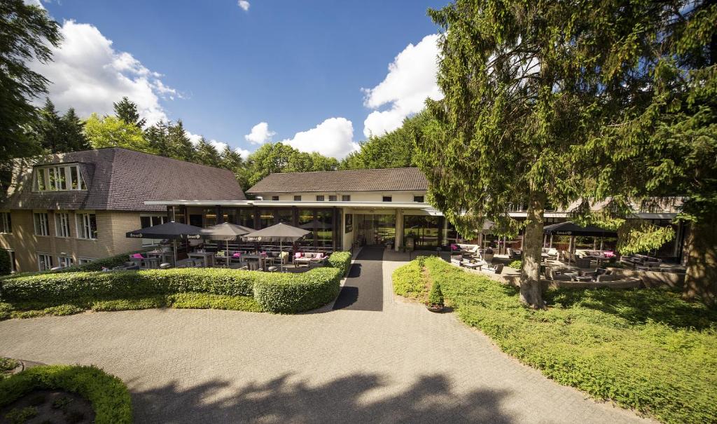 um edifício com um pátio com mesas e guarda-sóis em Bilderberg Hotel 't Speulderbos em Garderen