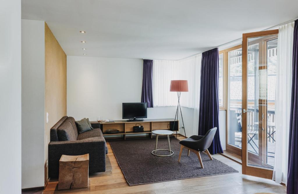 a living room with a couch and a desk with a television at Arlberg Lodges in Stuben am Arlberg