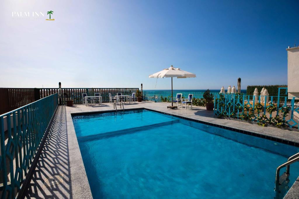 una piscina con sombrilla y el océano en Palm Inn Suites Hotel en Hurghada