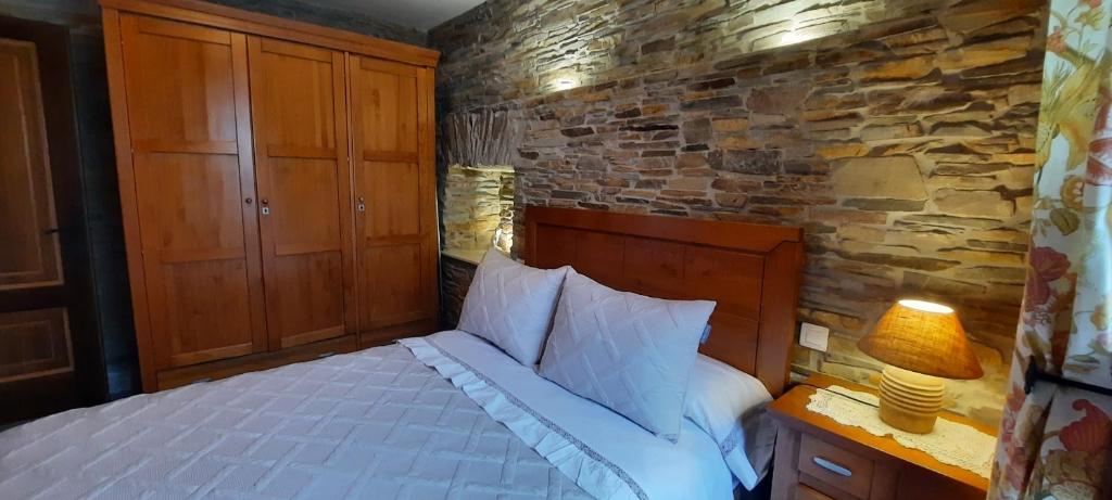 a bedroom with a bed and a stone wall at Apartamentos Turísticos Rosa in Ribadeo