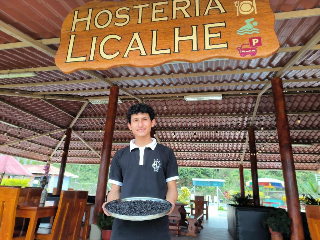 un homme tenant un plat dans un restaurant dans l'établissement Hosteria Licalhe, 