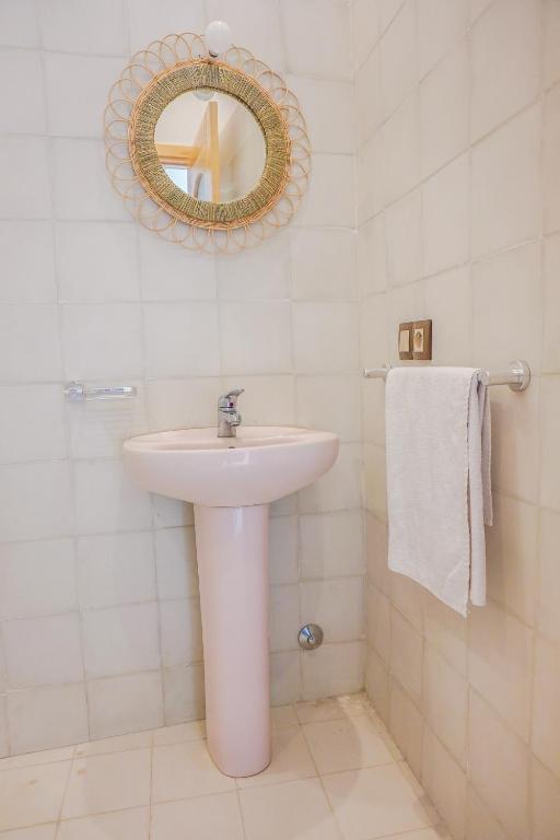 a white bathroom with a sink and a mirror at SurfAppart Morocco in Tamraght Ouzdar