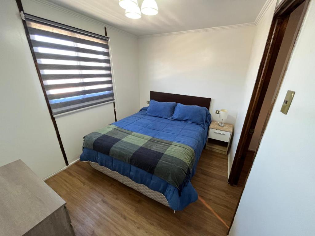 um quarto com uma cama azul e uma janela em Deptos Guacolda em Algarrobo