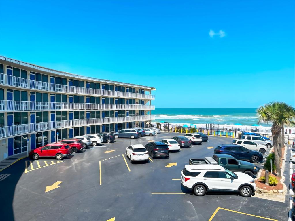 a parking lot with cars parked in front of a hotel at Outrigger Beach Club Resort in Ormond Beach