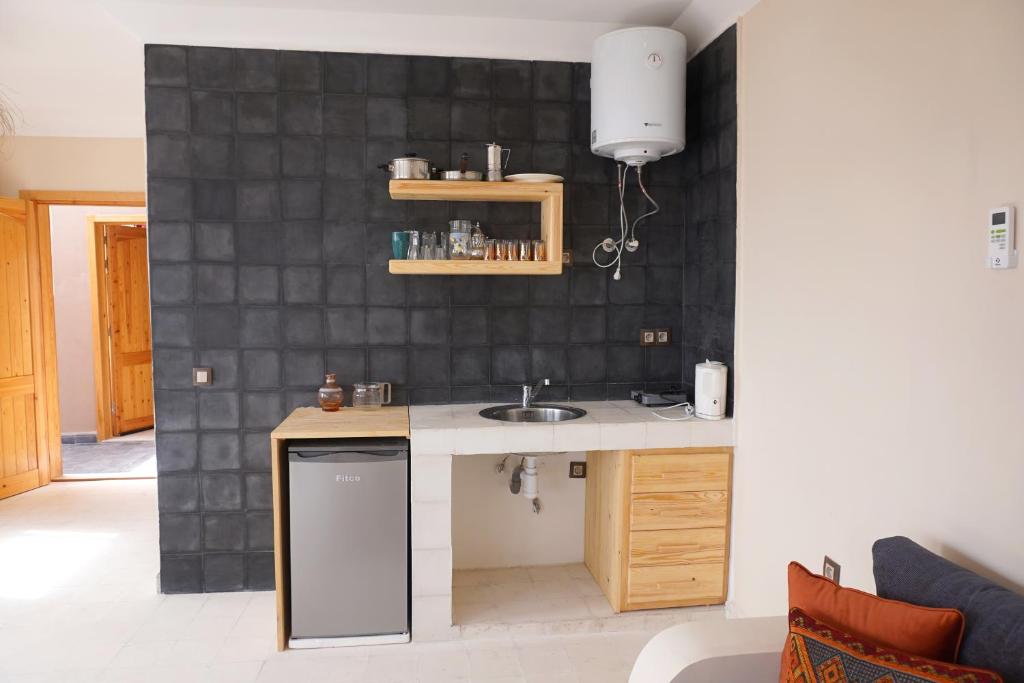 a kitchen with a sink and a black tiled wall at SurfAppart Morocco in Tamraght Ouzdar