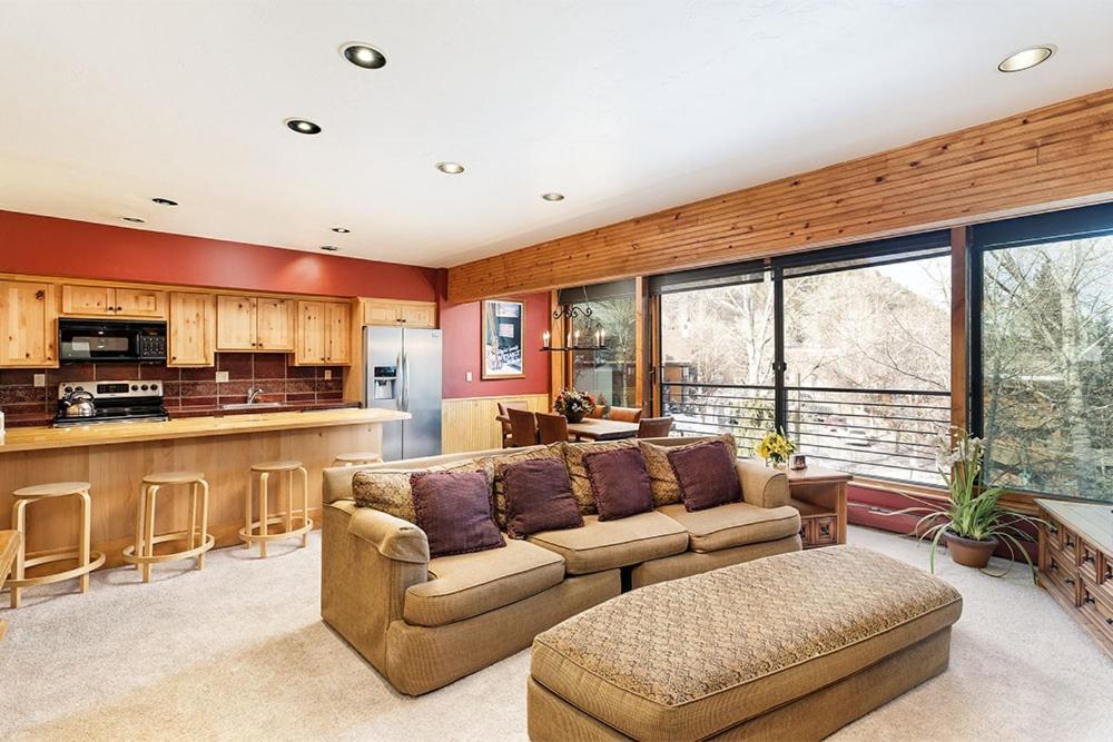 a living room with a couch and a kitchen at Durant Unit D3, Condo with Floor-to-Ceiling Windows, Fireplace, and more in Aspen