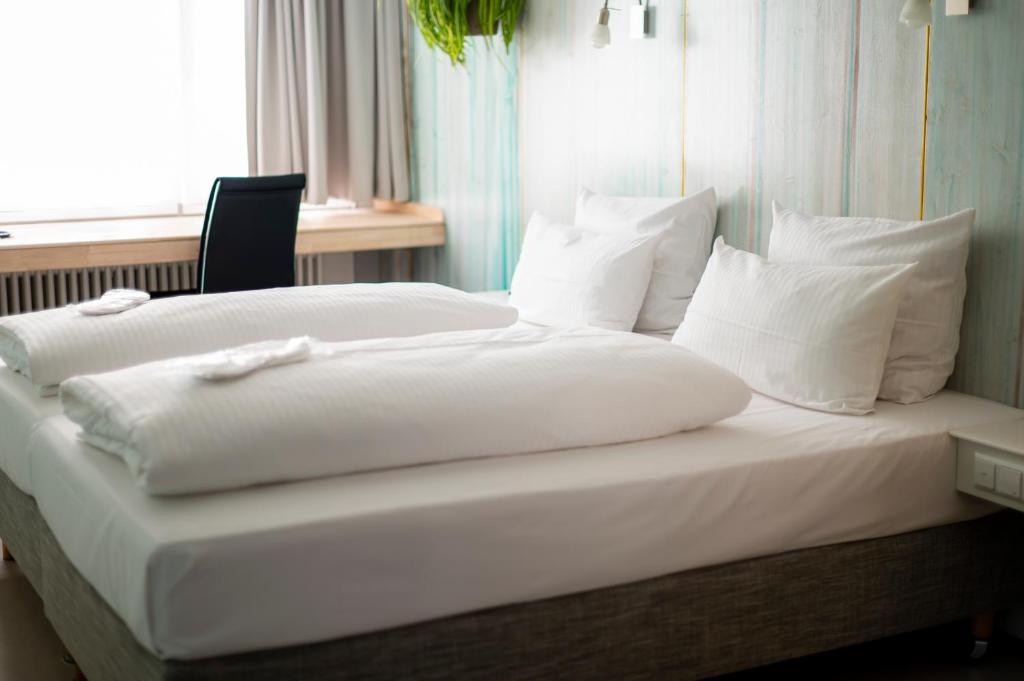 シュトゥットガルトにあるアバロン ホテル アイディアルのベッド(白いシーツ、枕付)