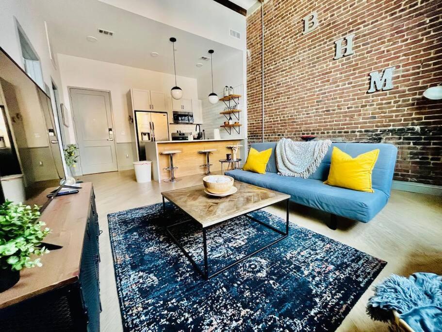 a living room with a blue couch and a brick wall at Trendy Condo! Close to everthing Downtown in Birmingham