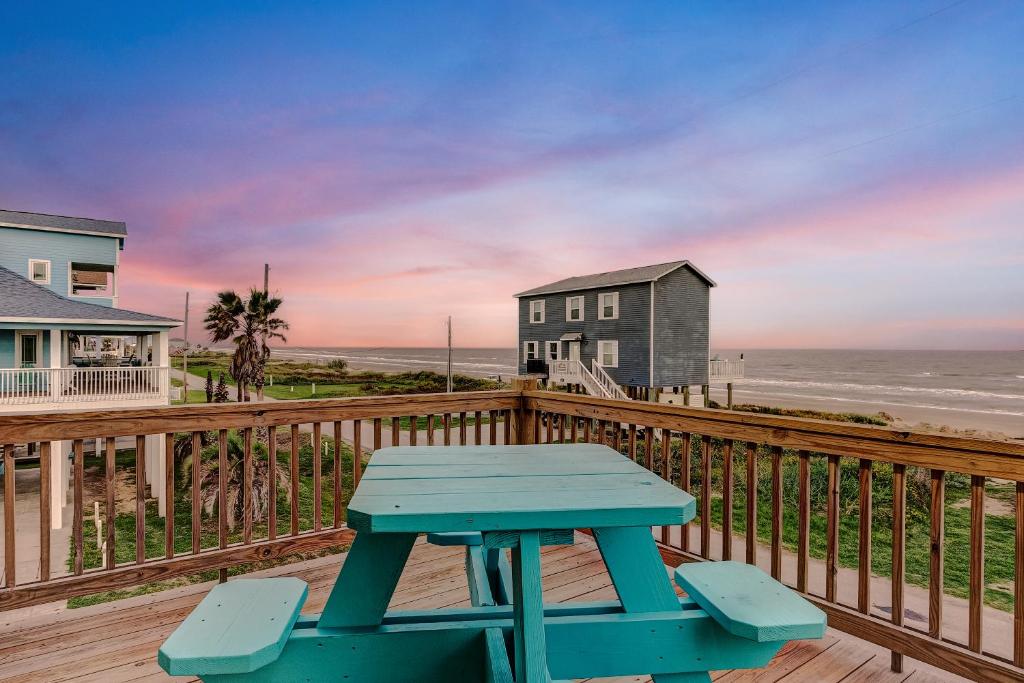 a blue picnic table on a deck with the beach at Beachfront - Hot Tub - BBQ - 14 Guests in Bolivar Peninsula