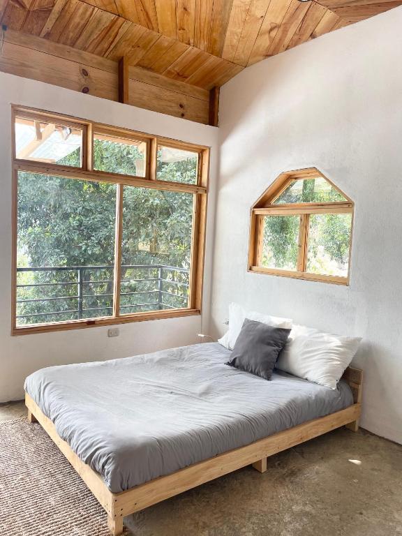 een bed in een kamer met 2 ramen bij EB5 Escape-Contemporary Stay, San Marcos La Laguna #1 in San Marcos La Laguna