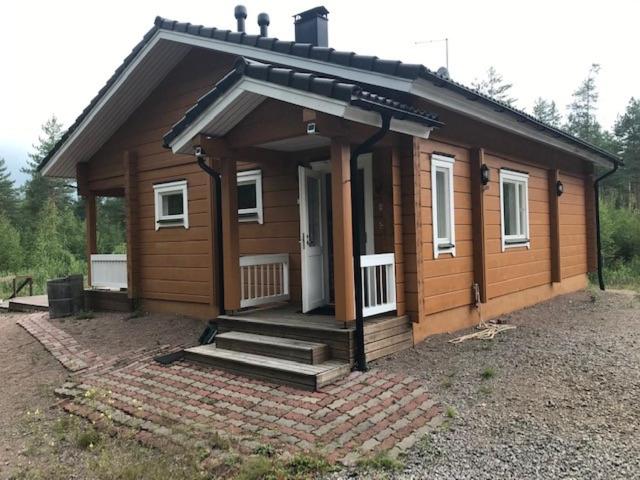 una pequeña casa de madera con porche y puerta en Modern cottage by the private lake en Lappeenranta