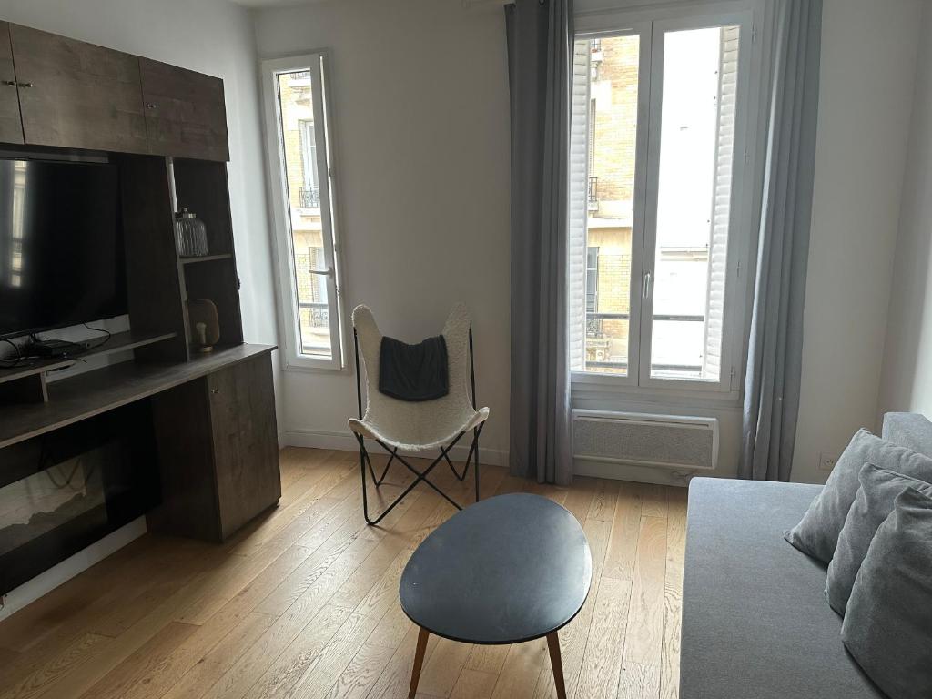 uma sala de estar com um sofá e uma cadeira em Cosy 2 pièces Parc Georges Brassens em Paris
