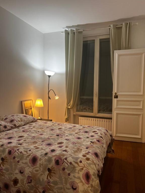 a bedroom with a bed and a window and a lamp at Eiffel Tower Oasis in Paris