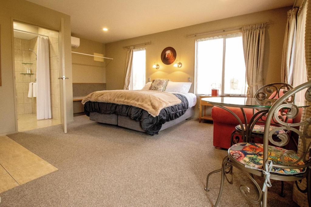 1 dormitorio con cama, mesa y ventana en Blue Ridge Studios and Bed & Breakfast en Te Anau
