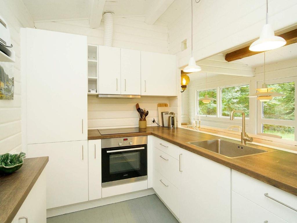a kitchen with white cabinets and a sink at Holiday home Vig XLIII in Vig