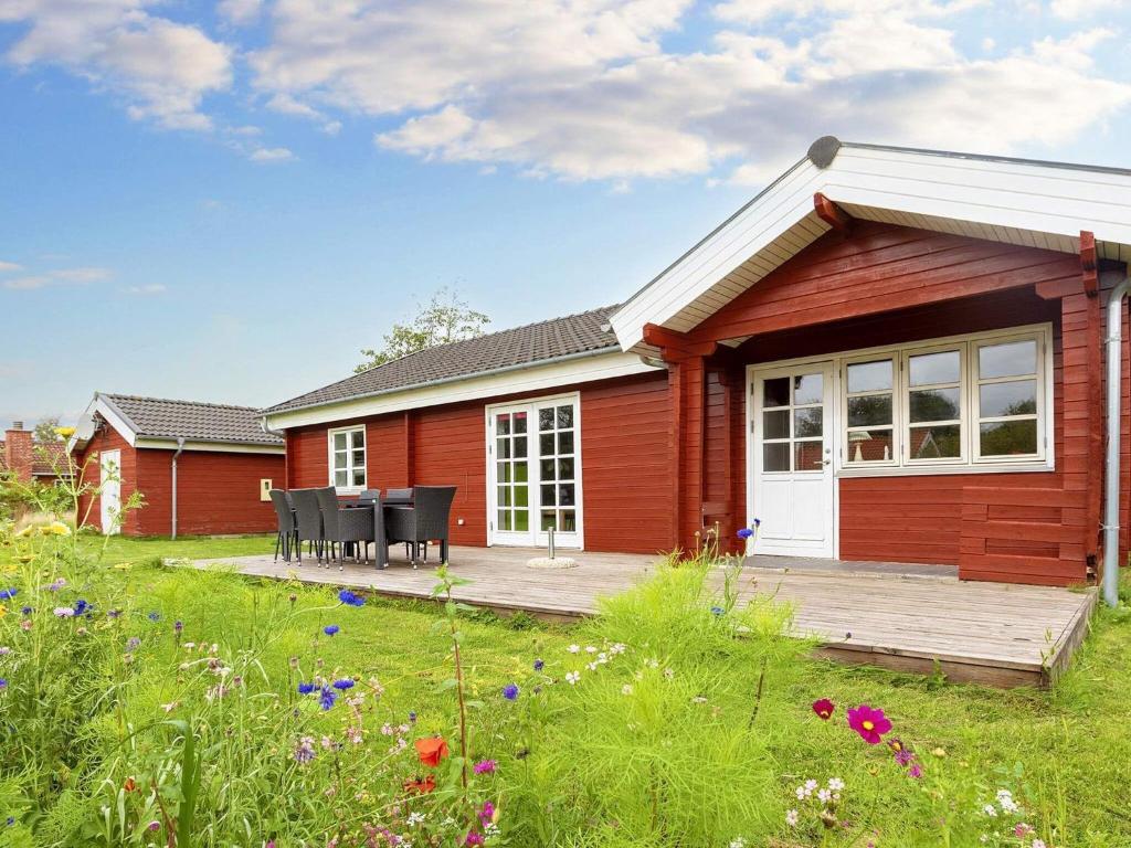 ein rotes Haus mit einer Terrasse und einem Tisch in der Unterkunft 8 person holiday home in Vinderup in Vinderup