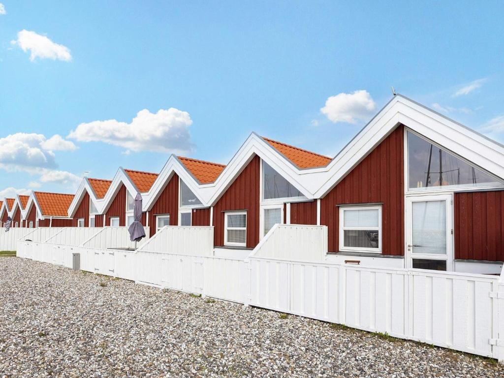 eine Reihe roter Häuser mit einem weißen Zaun in der Unterkunft 4 person holiday home in Nibe in Nibe