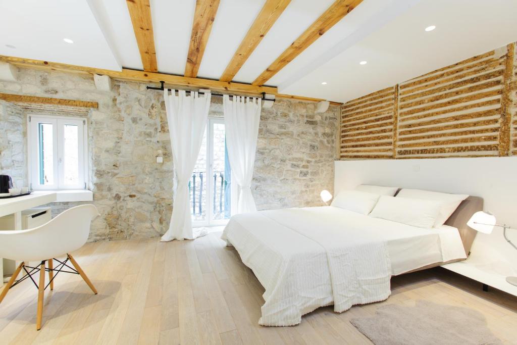 a bedroom with a large white bed and a desk at Grgur Ninski Rooms in Split