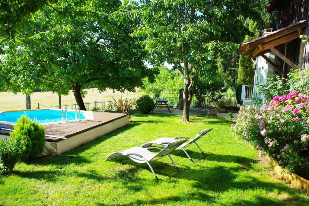 2 chaises assises dans l'herbe à côté d'une piscine dans l'établissement La Petite Maison, à Campsegret