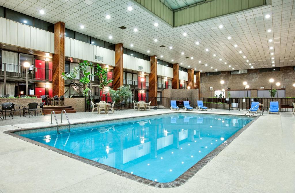 a large swimming pool in a building with blue chairs at Ramada by Wyndham Gulfport I-10 Diamondhead in Diamondhead