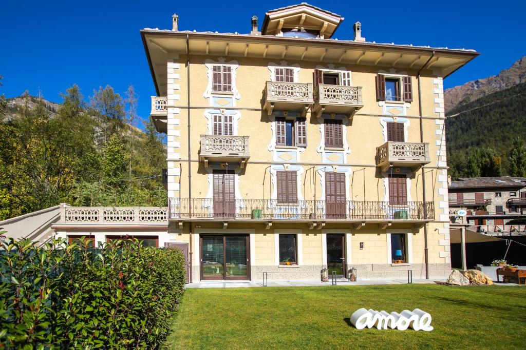 a large yellow building with a balcony on a yard at MAISON IDA in Courmayeur