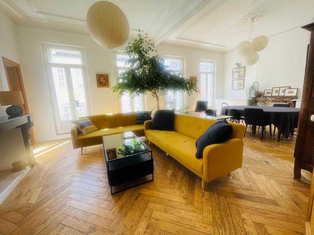 uma sala de estar com um sofá amarelo e uma mesa em Haussmannien lumineux em Marselha