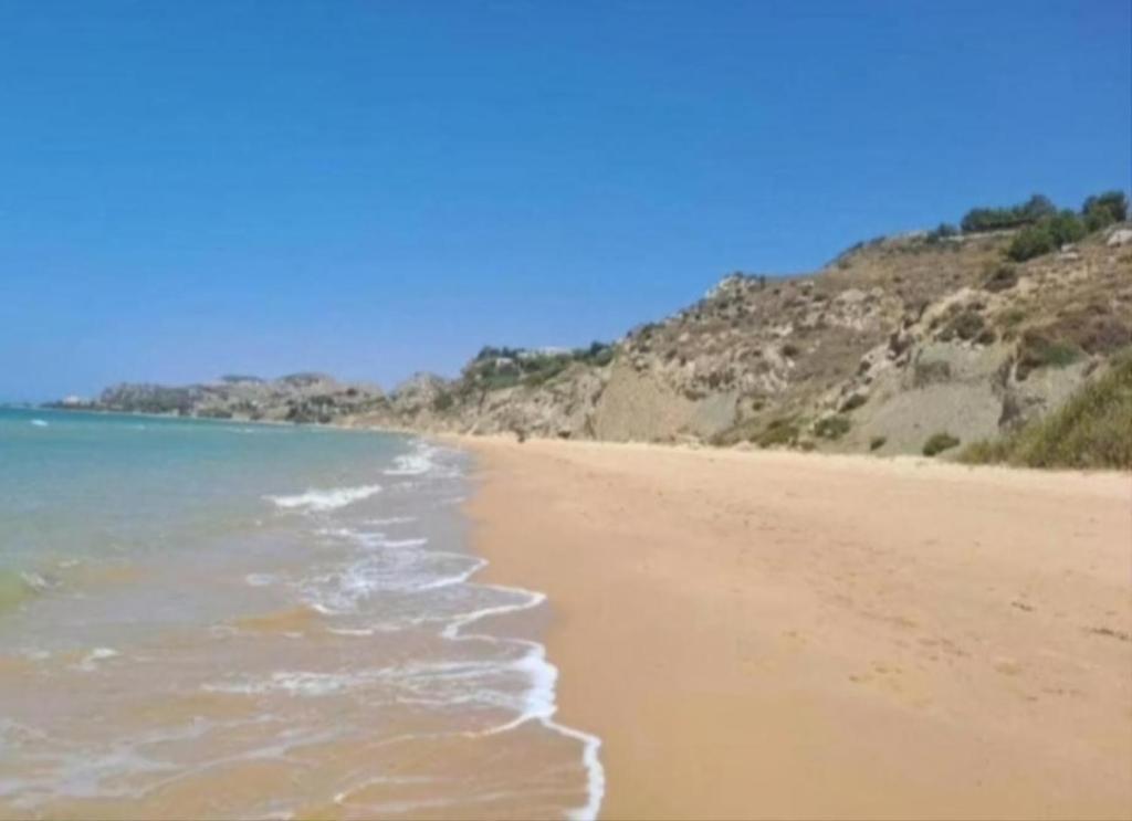 a sandy beach with the ocean and mountains in the background at La Foggia seaside paradise in Siculiana