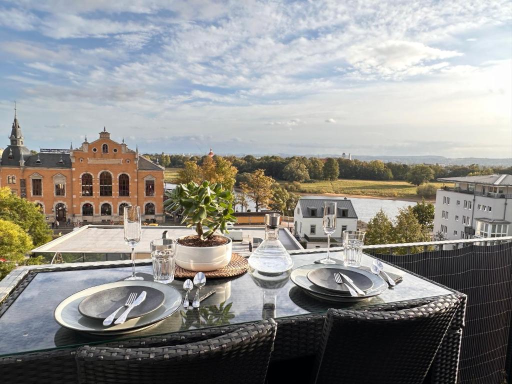 una mesa con platos y cubiertos en el balcón en Oasis Appart - Wohnen am Elbtal - Balkon - Netflix - Tiefgarage en Dresden