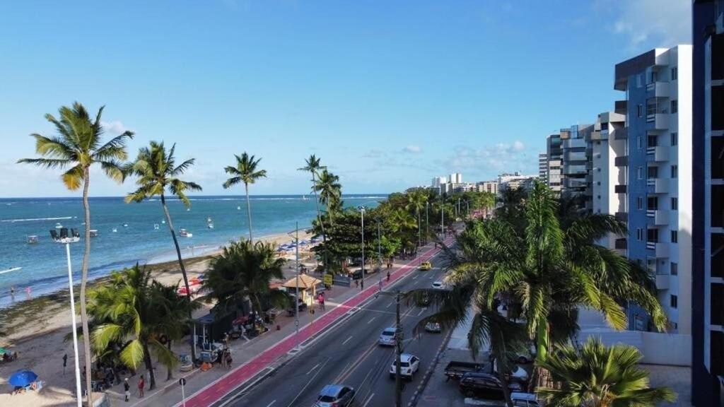 uma rua da cidade com palmeiras e o oceano em Rhodes I a Beira-mar da Jatiuca/Ponta Verde em Maceió