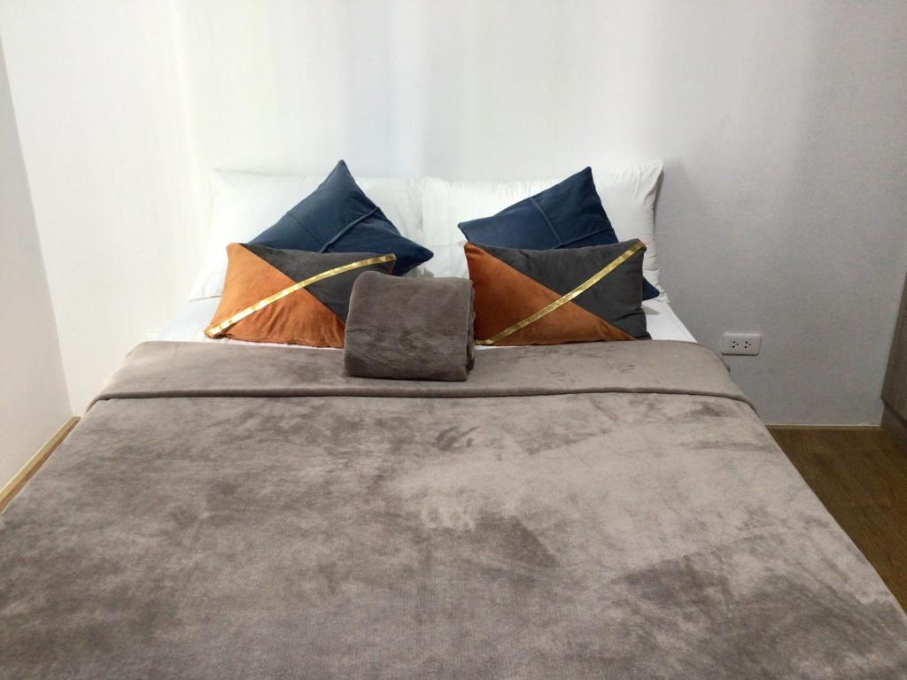 a bed with blue and orange pillows on it at 6F Balcony View Studio Mesatierra Garden Residences in Davao City