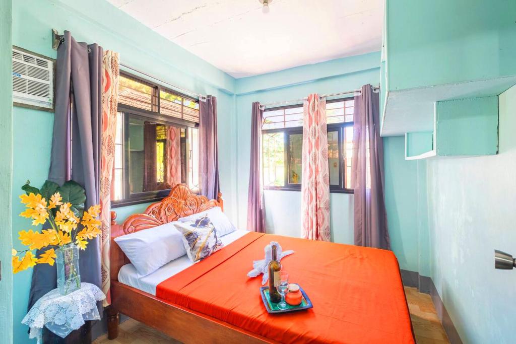 - une chambre avec un lit rouge et un vase de fleurs dans l'établissement Eyabonsha Homestay Vigan simple 2 units, à Aggay