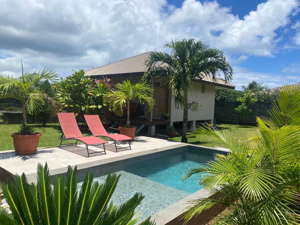 une villa avec une piscine et deux chaises roses dans l'établissement TAHITI - Bungalow Toah Piti, à Taravao