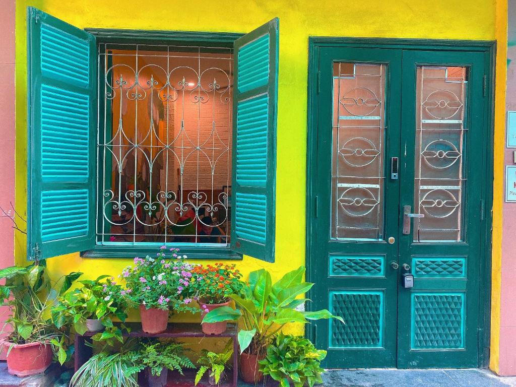 une maison avec des portes vertes et des fleurs devant elle dans l'établissement Anchie Home Lý Nam Đế- Ha Noi Train Street- Ha Noi Old Quarter, à Hanoï