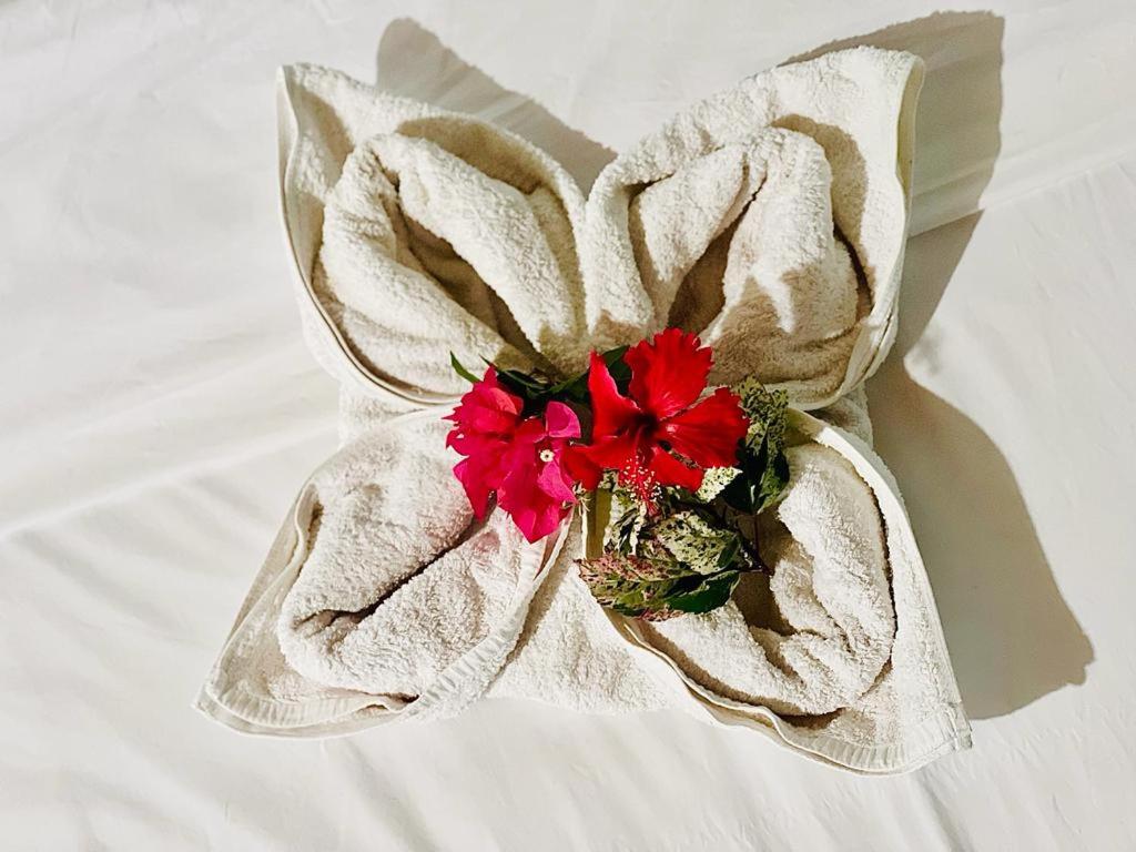 a white flower with red flowers on a bed at Kurnia Family Homestay & Restaurant! in Huu