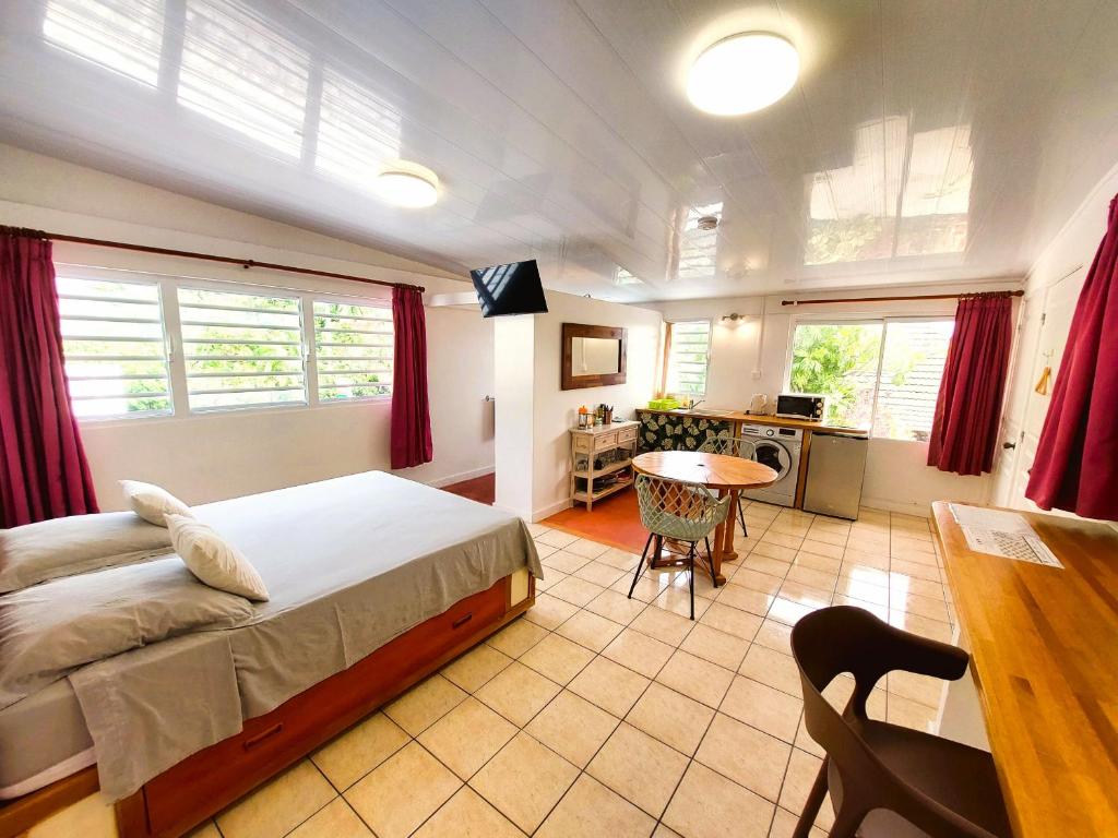 Cet appartement comprend une chambre avec un lit et une table ainsi qu'une cuisine. dans l'établissement RAIATEA - Studio TUMARAA, à Uturoa