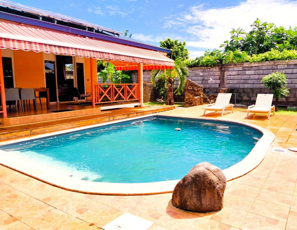 帕皮提的住宿－TAHITI - Lihei Pool House，一座房子前面的游泳池,有岩石