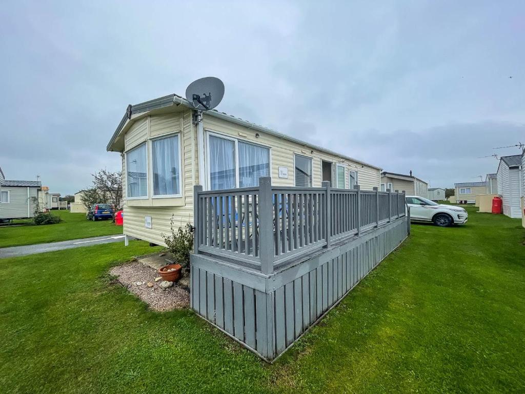 una casa con una valla en un patio en Brilliant Caravan With Wifi And Decking Near Pakefield Beach Ref 68040cr, en Lowestoft