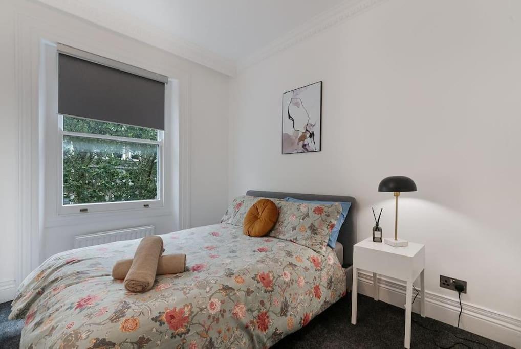a white bedroom with a bed and a window at Knightsbridge Two Bed Apartment in London
