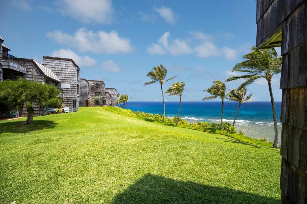 a lawn with palm trees and the ocean at Ocean View at Sea Lodge J4 in Princeville