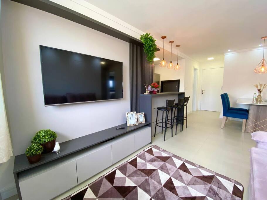 ein Wohnzimmer mit einem großen Flachbildfernseher an der Wand in der Unterkunft Apto central e próximo à praia in Torres