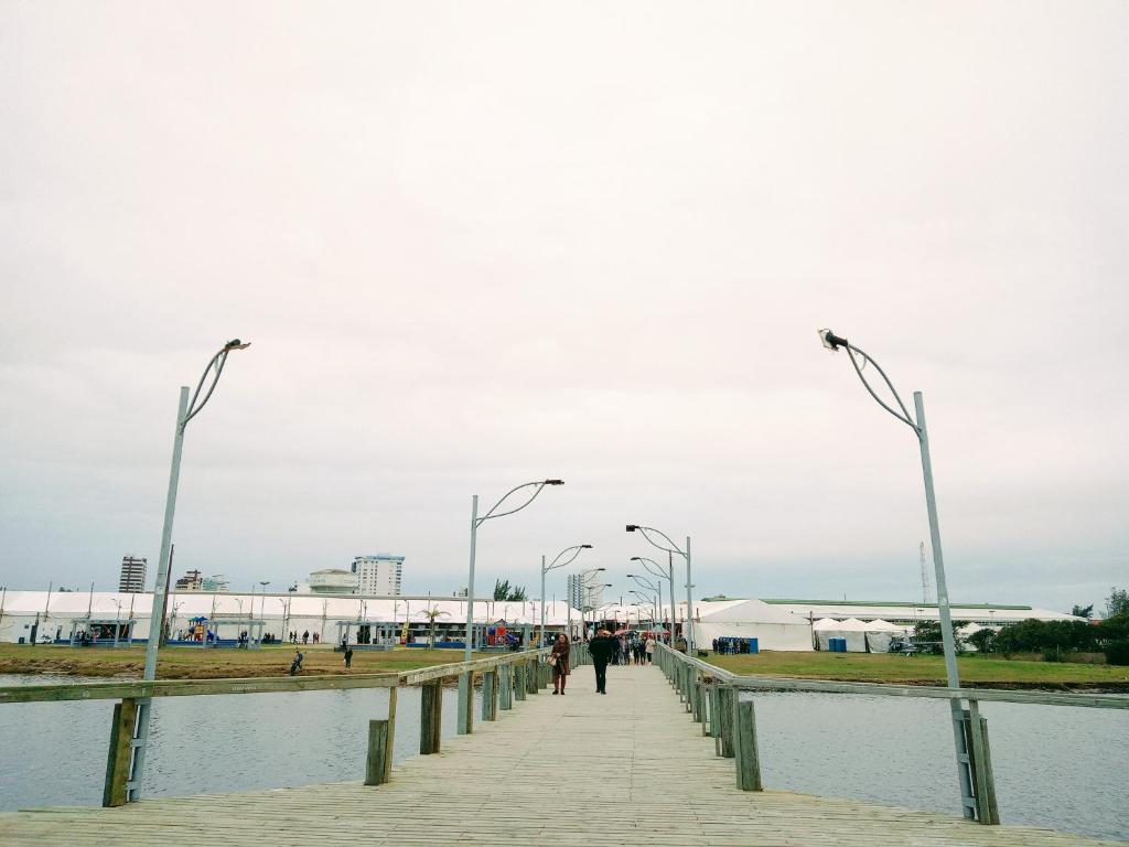 a boardwalk with street lights and a body of water at Kitnet da Elô in Tramandaí