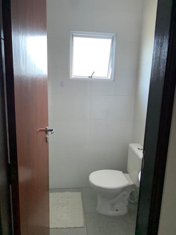 uma casa de banho com um WC e uma janela em Apartamento Maranduba em Ubatuba