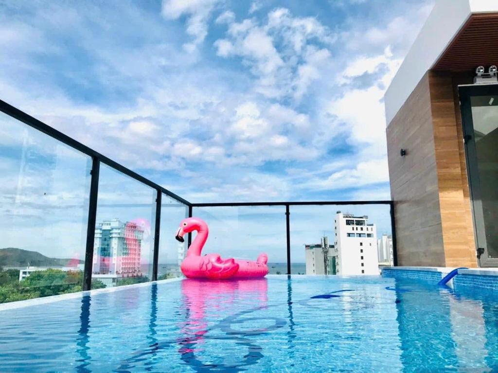 a pink swan sitting on the edge of a swimming pool at Bel-air Hotel in Quy Nhon
