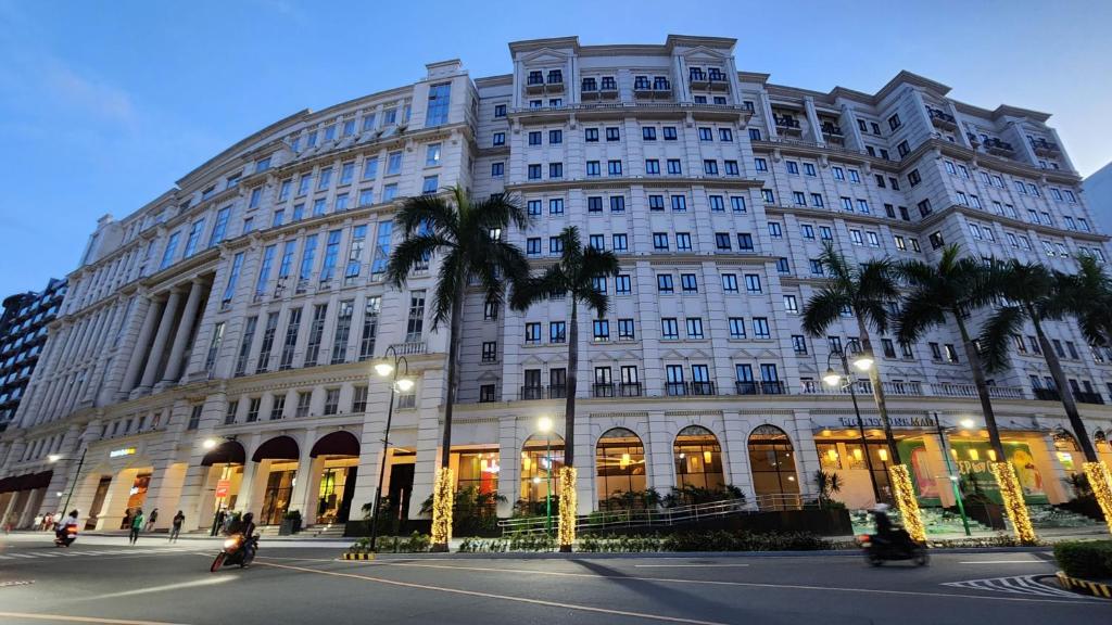 un gran edificio con palmeras delante en House of B&Y at 101 Newport across NAIA T3 en Manila
