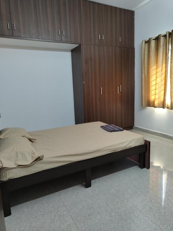 a bedroom with a bed with wooden cabinets and a window at Shree 53 1BHK in Bangalore