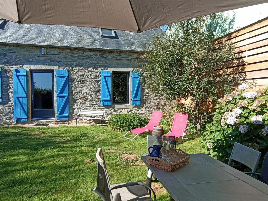 une terrasse avec des chaises roses et une table avec un parasol dans l'établissement Gite in Ploneour-Lanvern, à Plonéour-Lanvern